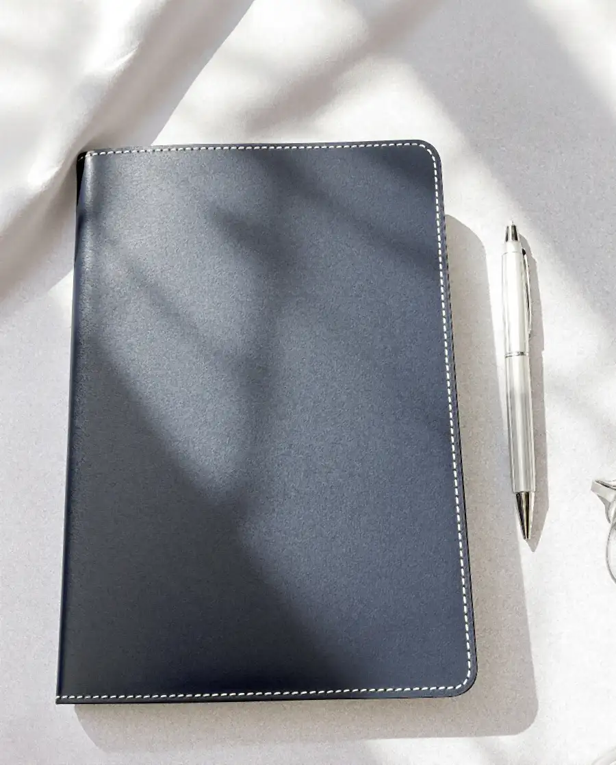 A leather notebook and pen on linen